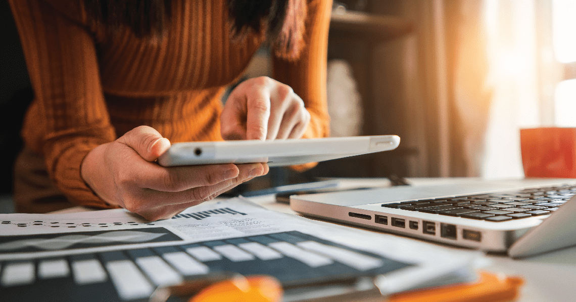 Woman working on tablet at her desk with papers beneath her