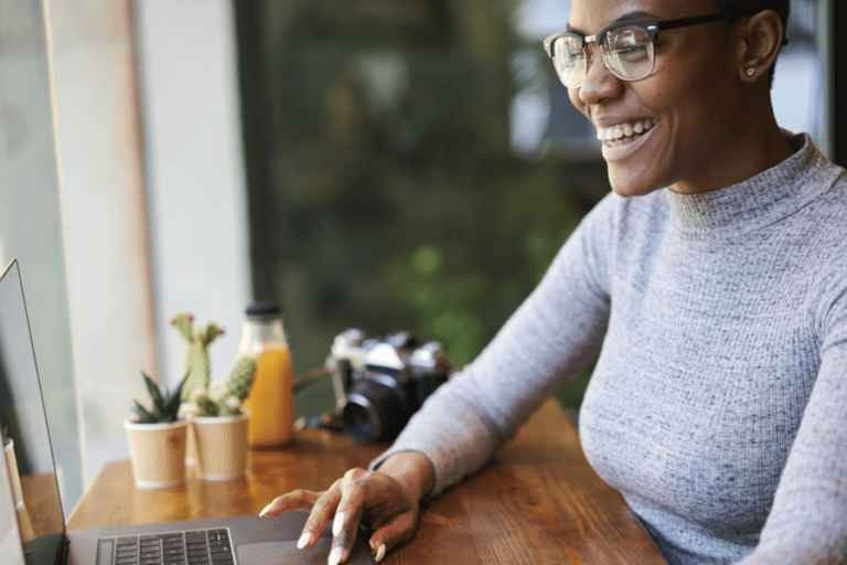 Woman smiling on her laptop in a right office